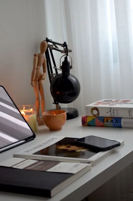 A minimalist office desk featuring an iMac, a lamp, and stationery, ideal for technology-themed backgrounds.